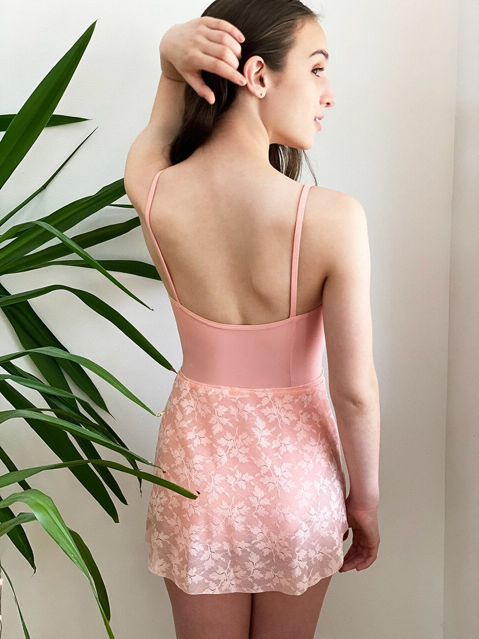 Model wearing a pink leotard with a matching floral pink mesh skirt