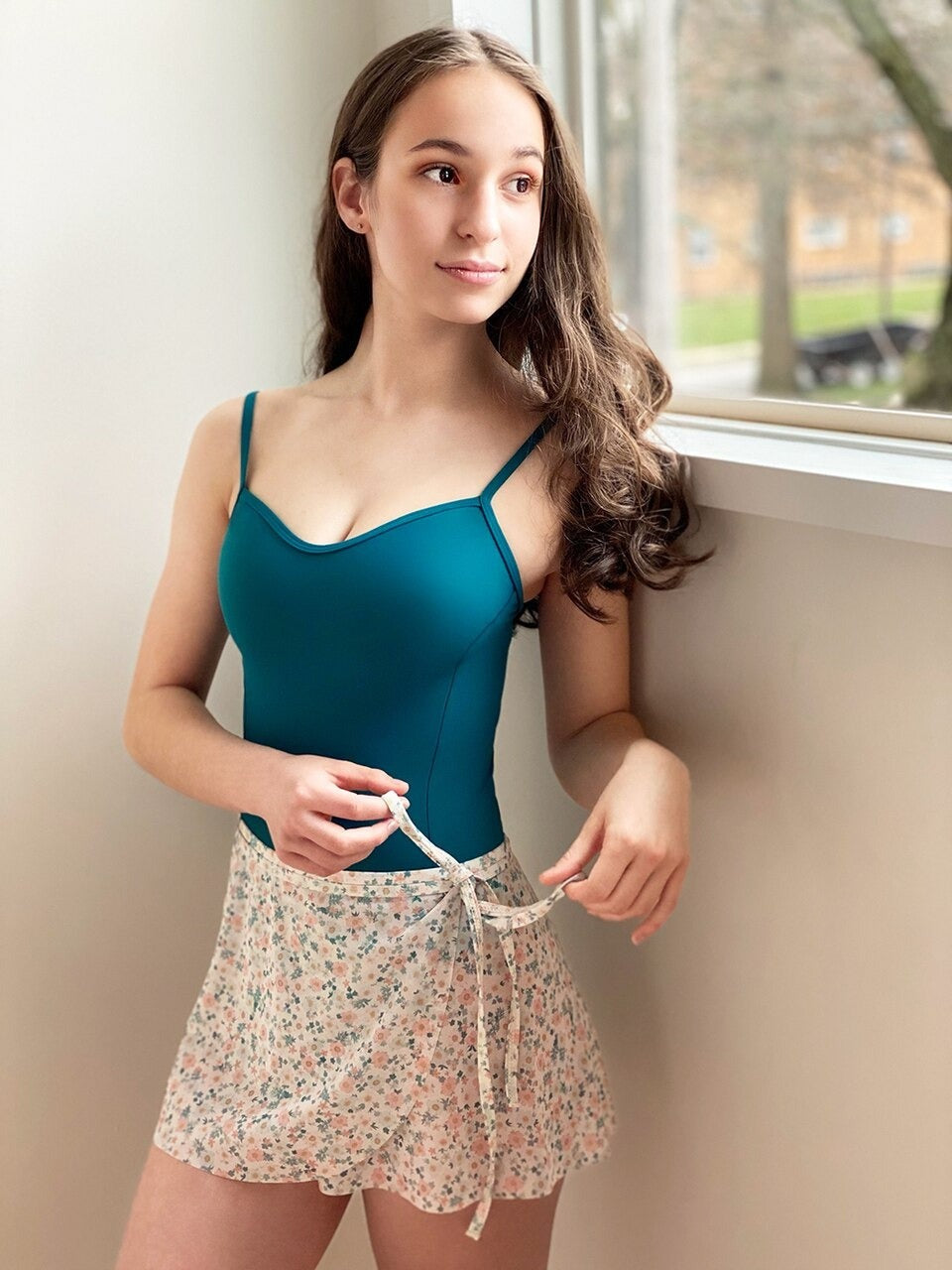Model wearing a teal leotard with a matching floral wrap skirt