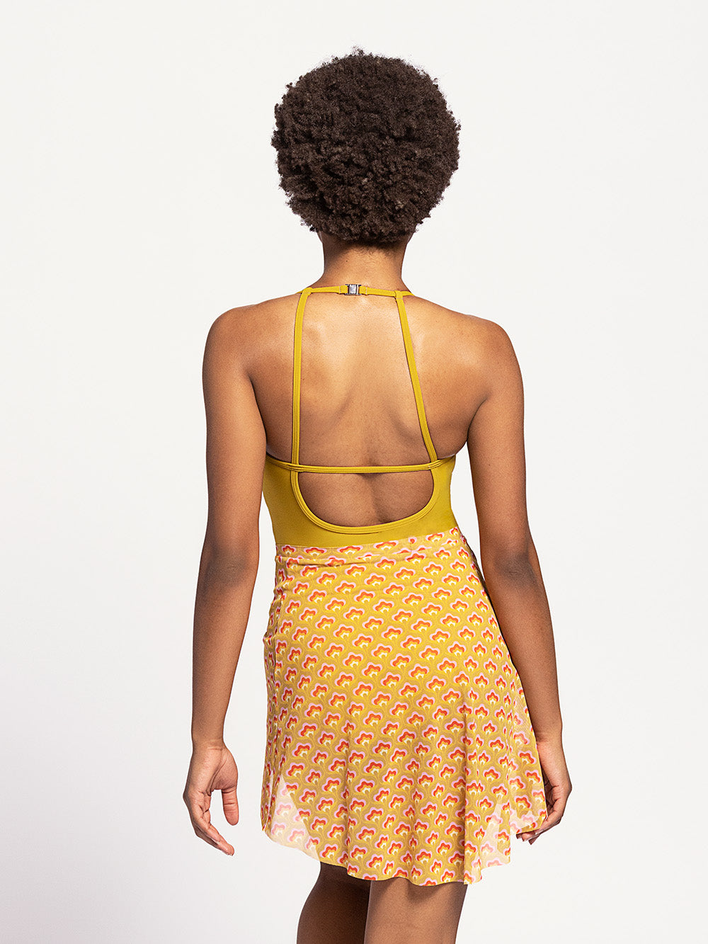 Model in mustard colored mesh skirt and pistachio colored leotard