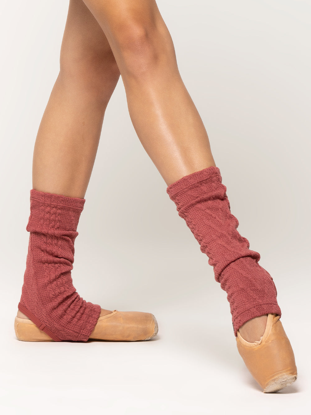 Front of stirrup ankle length leg warmers in dark pink cable knit