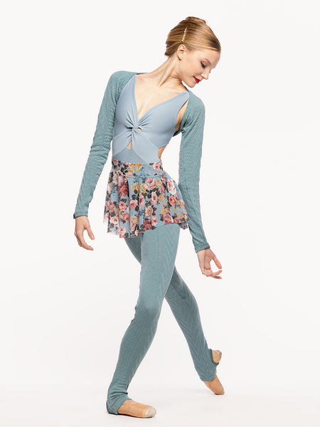 Model is wearing a cable knit shrug in Ocean blue green, light blue leotard with twist detail, light blue floral print mesh flare skirt, and matching Ocean knit long leg warmers