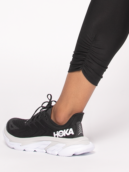 Model showcasing gathered detail at the ankle of black leggings