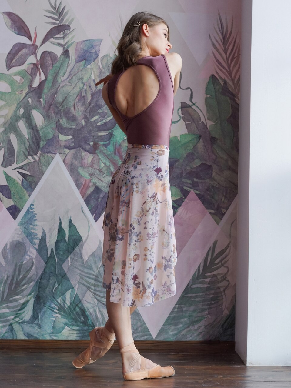 Model wearing a shiny dark mauve leotard with a matching white floral pattern mesh skirt
