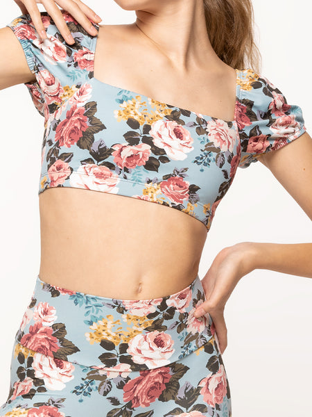 Model is wearing light blue floral print short activewear crop top with puff sleeves and matching high waisted leggings