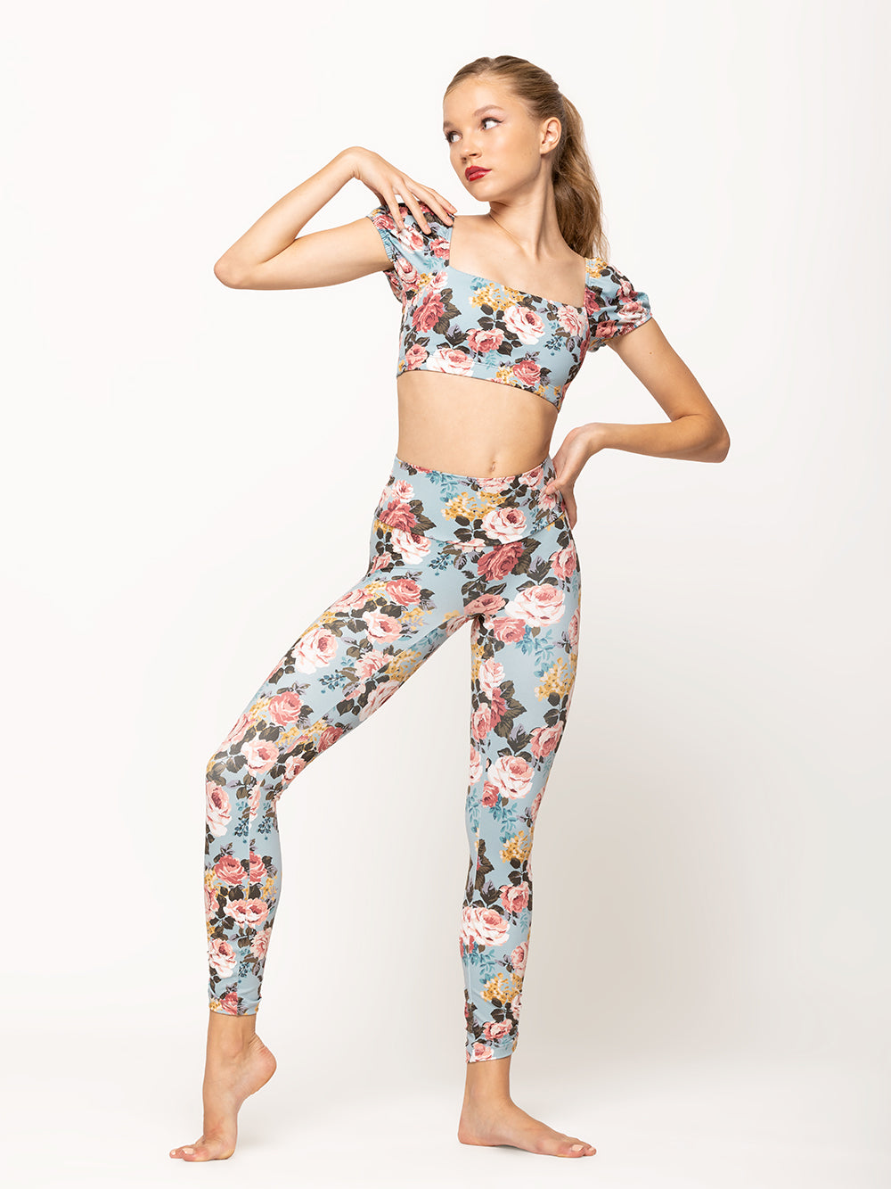 Model is wearing light blue floral print short activewear crop top with puff sleeves and matching high waisted leggings