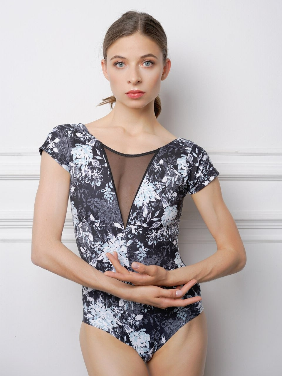 Model wearing a black and white floral pattern leotard with mesh detail