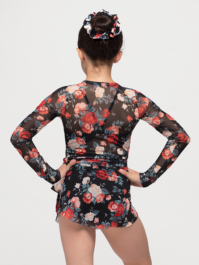 back of model in wrap top with red and white rose floral pattern and black mesh backdrop