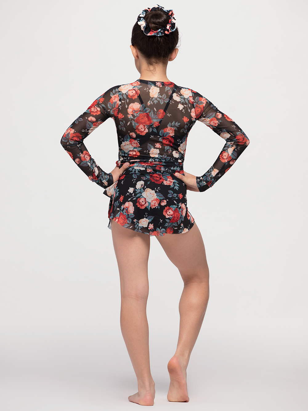back of model in wrap top with red and white rose floral pattern and black mesh backdrop