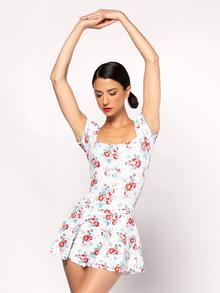 Front of model in leotard with floral pattern featuring red flowers on white backdrop with matching skirt