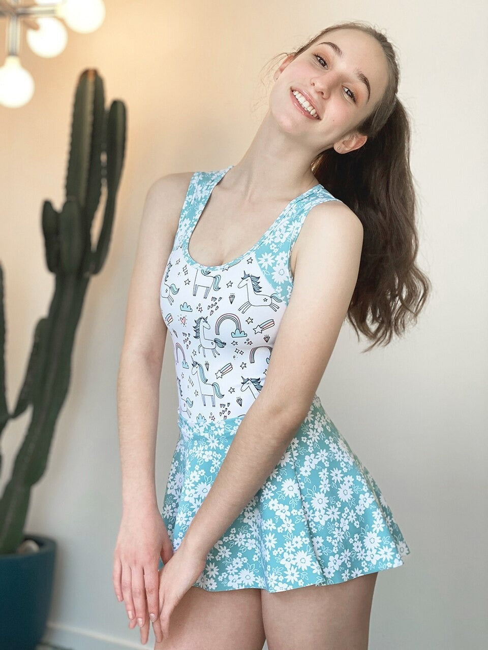Model wearing a unicorn pattern leotard with blue floral straps and skirt