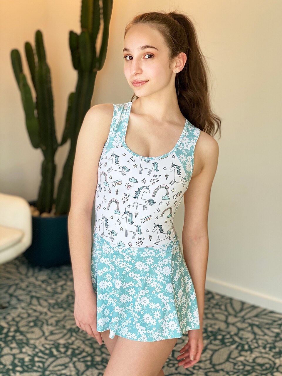 Model wearing a unicorn pattern leotard with blue floral straps and skirt