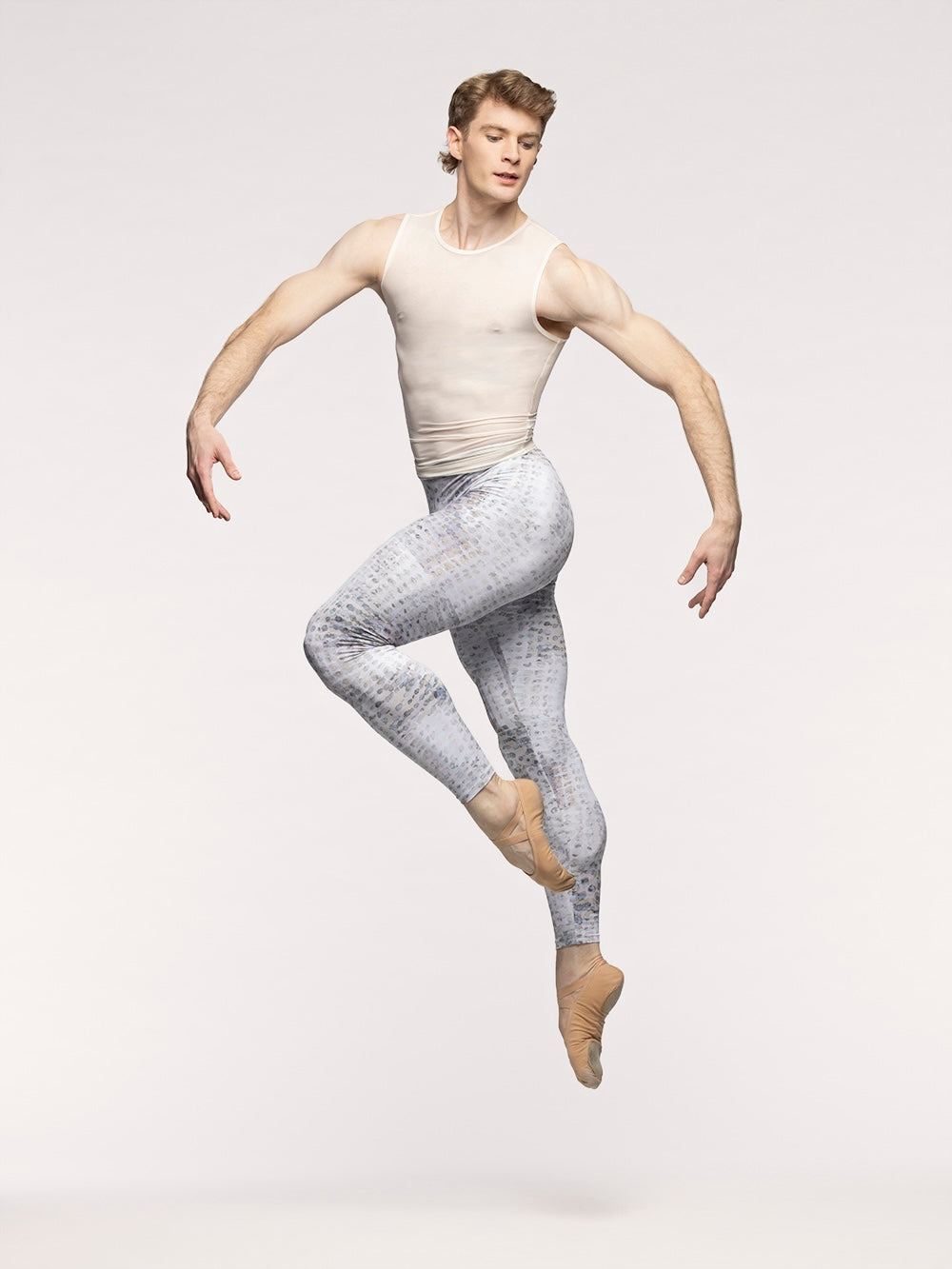 Eleve Dancewear Seth Shirt in Cream Mesh print color, profile view of dancer jumping on cou-de-pie en dedans