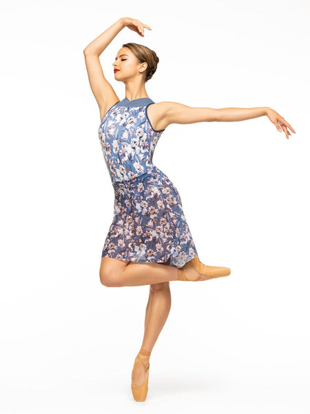 Model is wearing blue floral print bodysuit with blue mesh high neck and navy blue trim paired with matching floral mesh high low skirt.