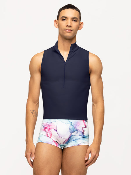 Model is wearing dark navy blue men's activewear sleeveless shirt with high color and front zipper. Paired with blue, purple, and pink watercolor dance shorts.