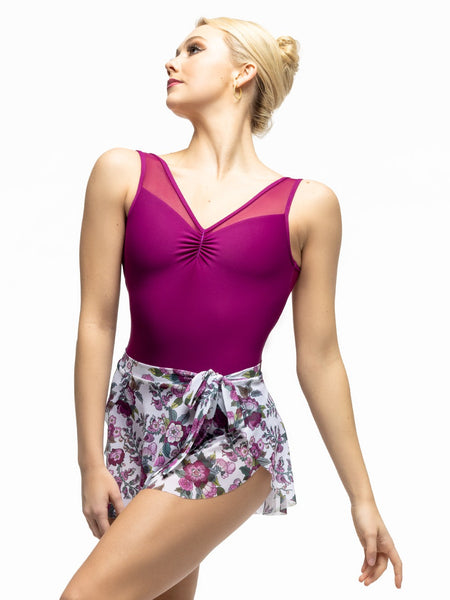 Model is wearing white and magenta floral print mesh skirt with side bow tie and magenta leotard with front pinch.