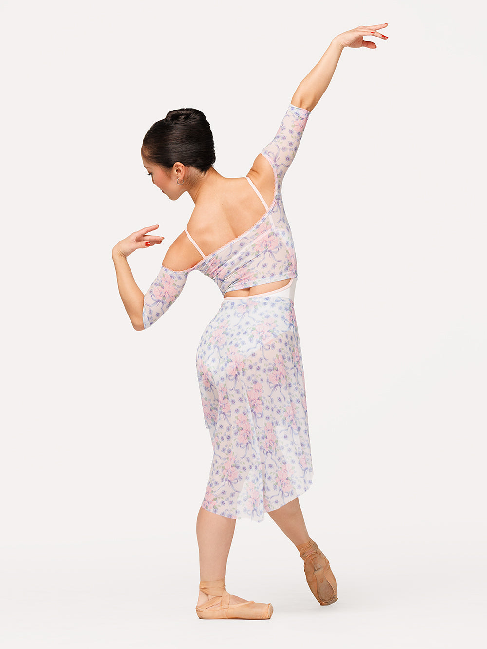 Eleve Dancewear Open Shoulder Crop Top and Long High-Low Skirt in Flowers & Bows Mesh in Encore Mesh print, back view of dancer on tendu devant croise