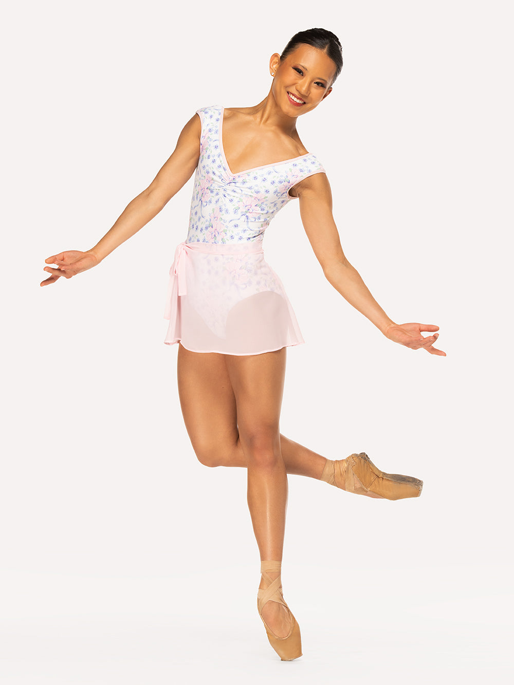 Eleve Dancewear Chiffon Mini Tie Skirt in Light Pink color, front view of dancer on pique passe crossed