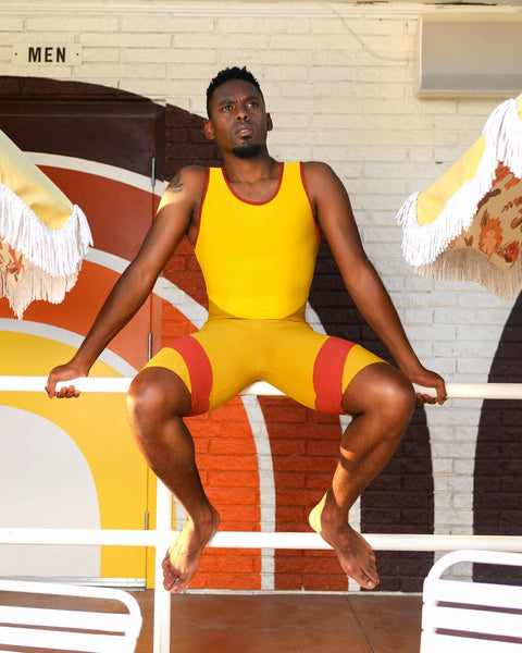 Model wearing a yellow mens unitard with red accents 