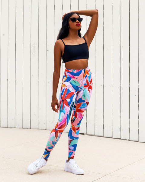 Model wearing a black athletic crop top sports bra and bright multi color pattern leggings high waisted active wear yoga set