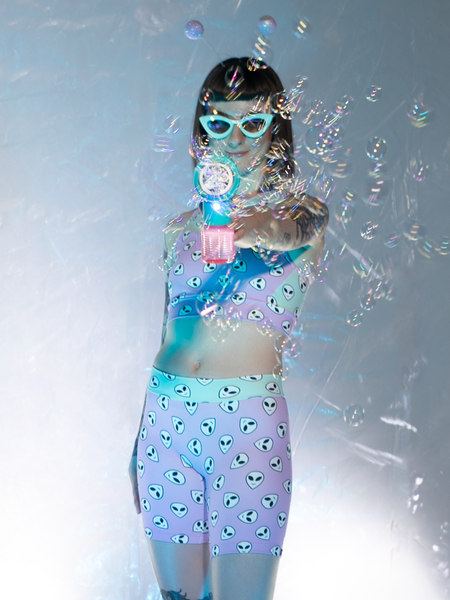 Front view of model in Orchid pink and mint green alien face print crop-top and shorts with bubble blaster 