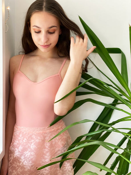 Model wearing a pink leotard with pink lace mesh skirt