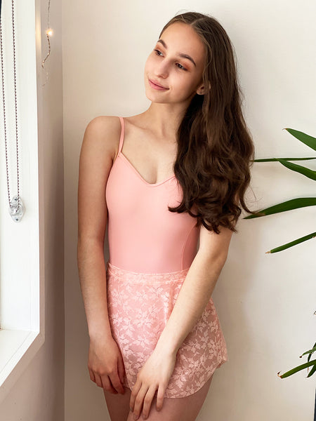 Model wearing a pink leotard with a matching pink lace mesh skirt