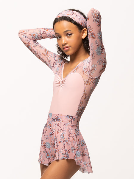 Model is wearing light pink bodysuit with pink floral print mesh long sleeves and matching mesh skirt and headscarf