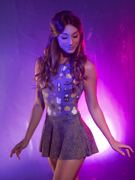 Front close up Model in leotard with Halloween characters on purple background with purple plum cheetah print skirt  looking down smiling 