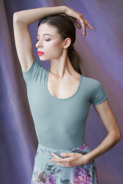 Model wearing a gray blue leotard  with a matching floral pattern mesh skirt