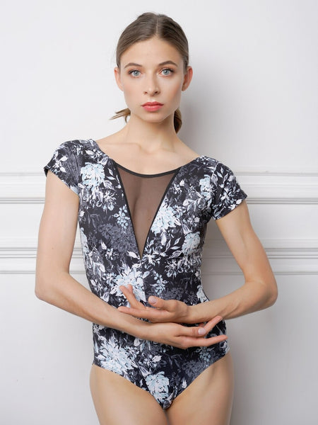 Model wearing a black and white floral pattern leotard with mesh detail