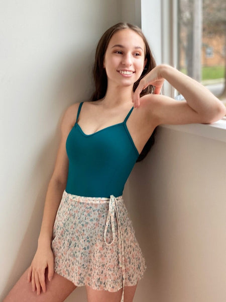 Model wearing a teal leotard with a matching floral wrap skirt